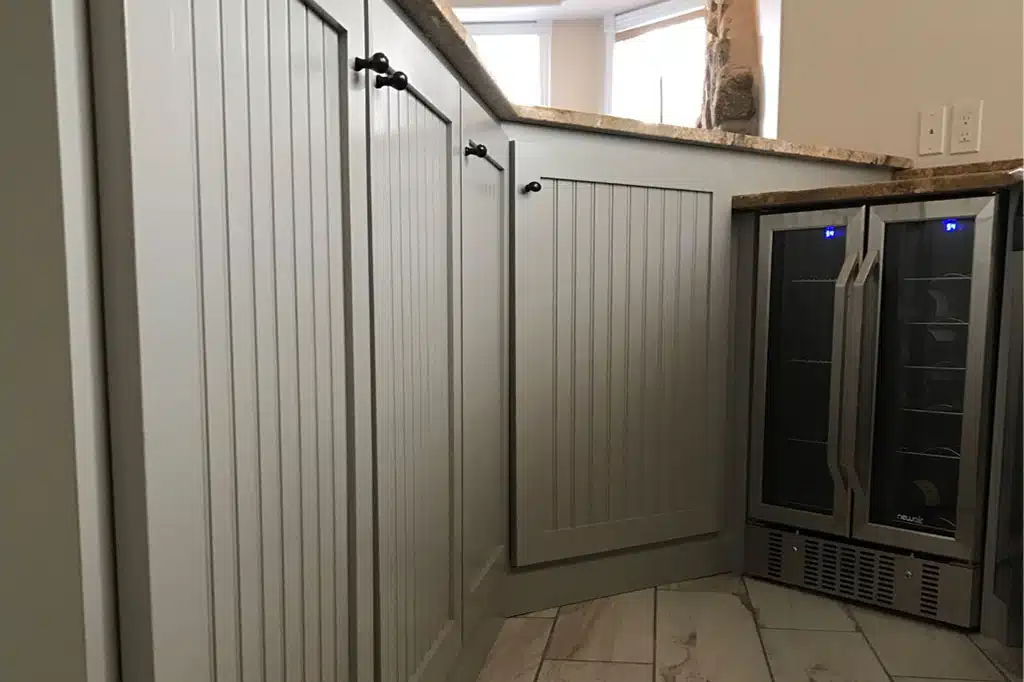 An American Town Painting of a kitchen Cabinet alongside a wine cooler.