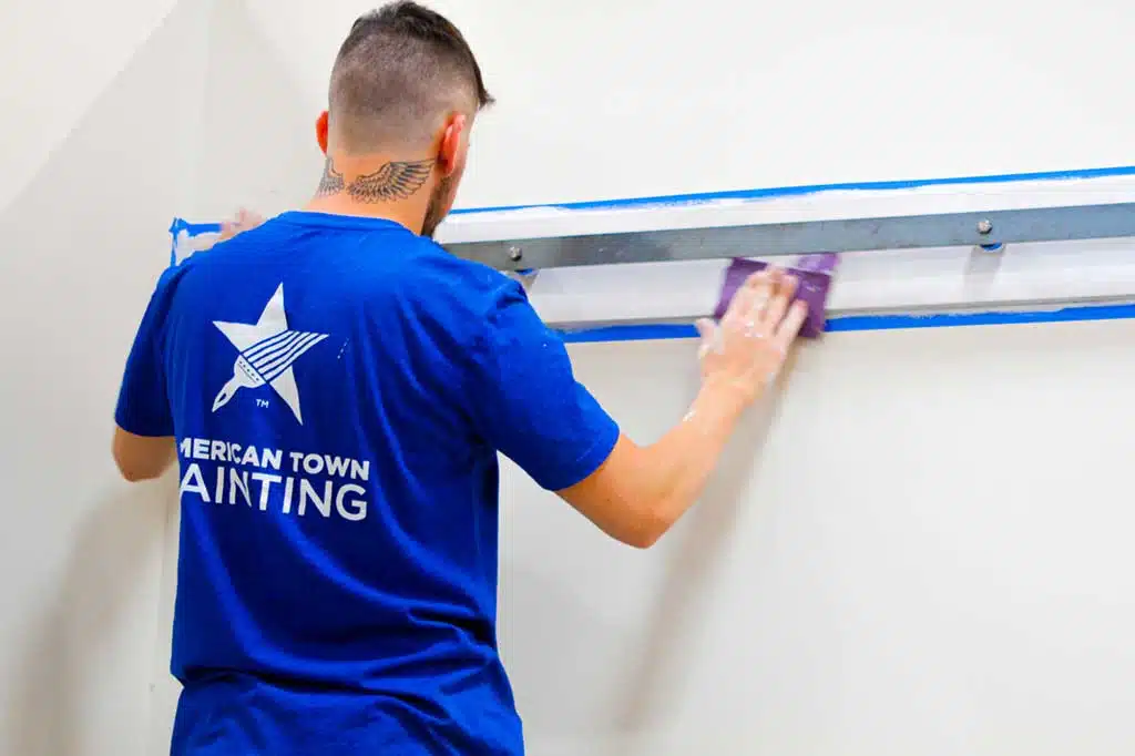 A man in a blue shirt painting a wall, representing the theme of American Town Painting.