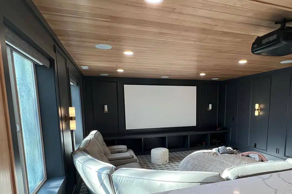 Home theater room painted in dark navy with wood plank ceiling