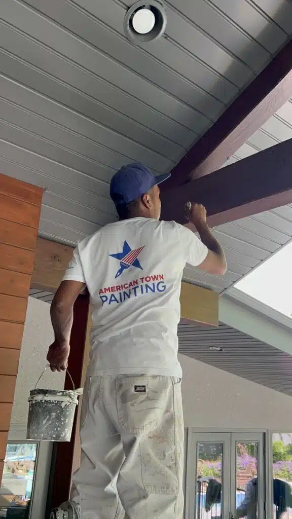 A man painting a porch featuring a star design, showcasing his work in an American town setting.