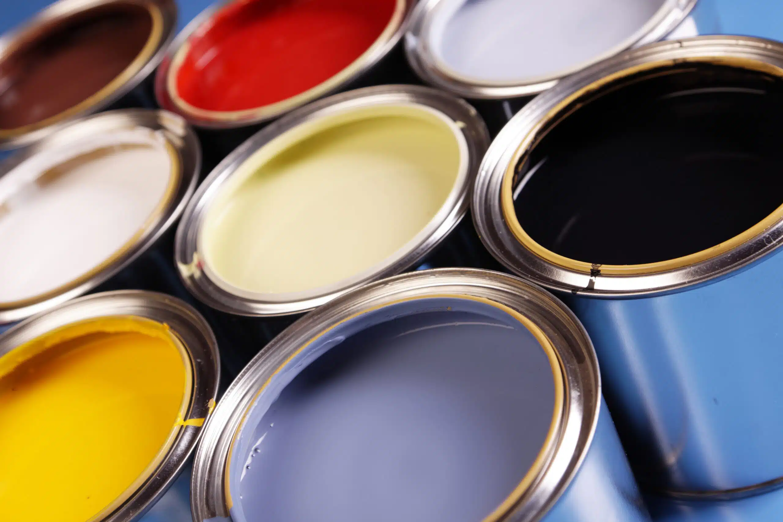 A collection of paint cans in various colors, labeled for American Town Painting, showcasing vibrant hues for projects.